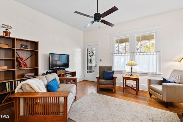 living area featuring baseboards, wood finished floors, a ceiling fan, and vaulted ceiling