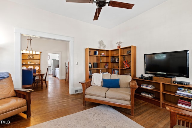 living room featuring visible vents, baseboards, a ceiling fan, and wood finished floors