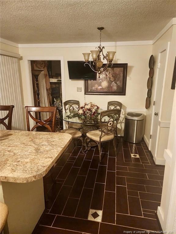 dining room featuring an inviting chandelier, a textured ceiling, and wood finish floors