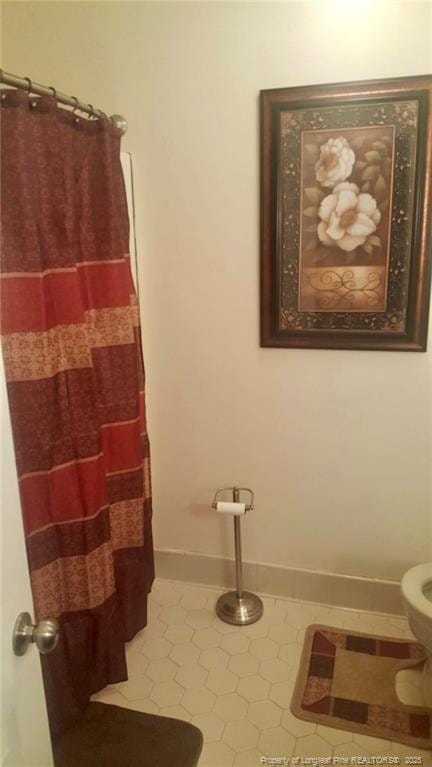 bathroom featuring tile patterned flooring, a shower with curtain, toilet, and baseboards