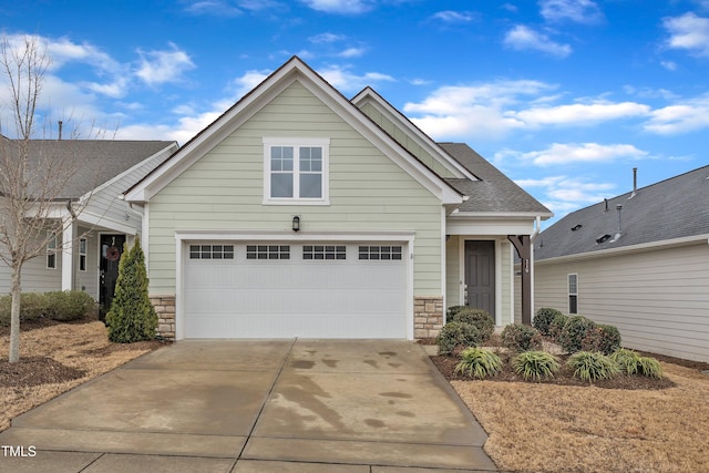 craftsman-style home with a shingled roof, stone siding, an attached garage, and concrete driveway