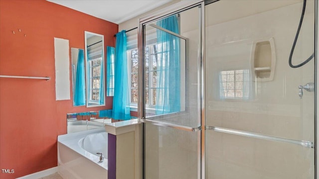 bathroom with a stall shower, a garden tub, and a healthy amount of sunlight