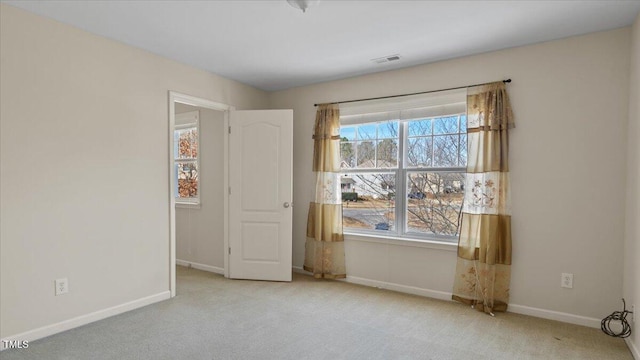 unfurnished room with visible vents, baseboards, and light colored carpet