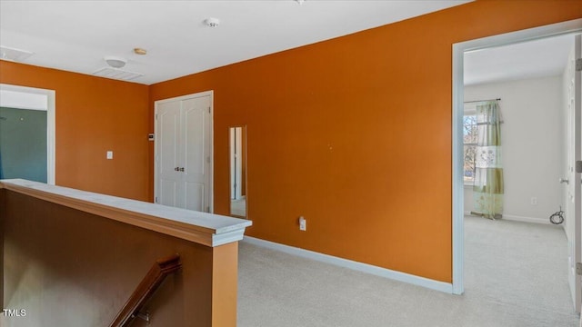 corridor with an upstairs landing, light colored carpet, and baseboards