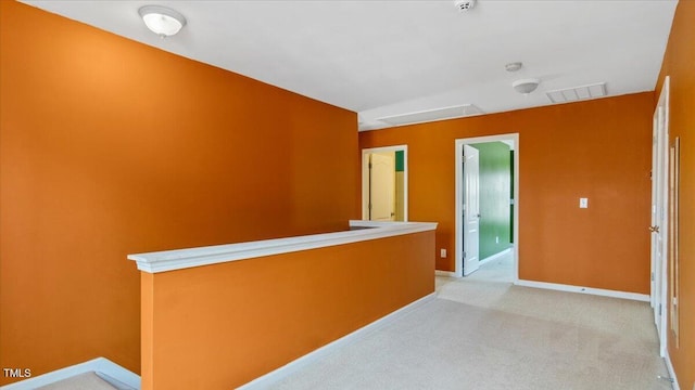 hall with light carpet, attic access, visible vents, baseboards, and an upstairs landing