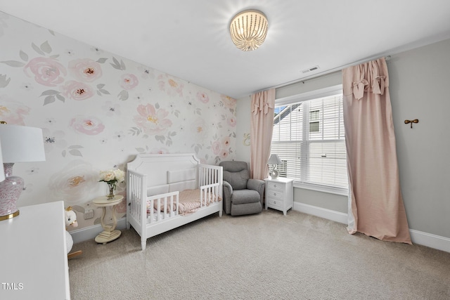 carpeted bedroom featuring visible vents, a crib, baseboards, and wallpapered walls