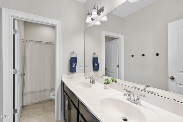 full bathroom with double vanity, tile patterned flooring, a sink, and toilet