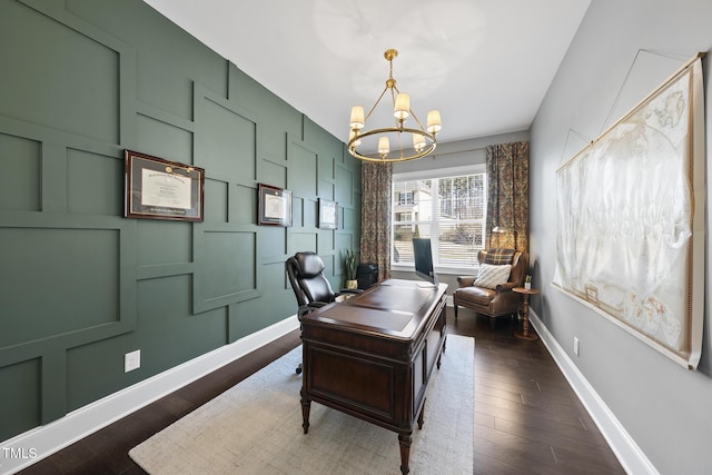 office with dark wood-type flooring, a notable chandelier, a decorative wall, and baseboards