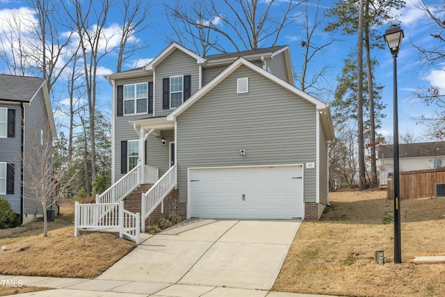 traditional-style house featuring a garage, driveway, and central AC unit