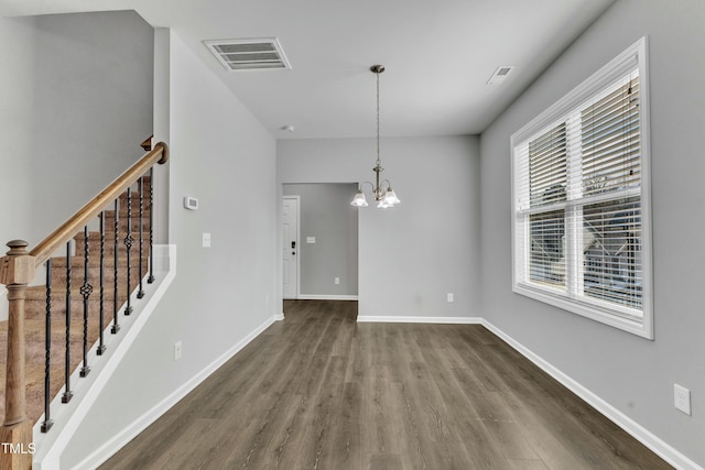 unfurnished dining area with baseboards, visible vents, stairway, dark wood-style flooring, and a chandelier