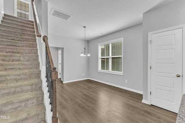 foyer entrance with stairway, visible vents, dark wood-type flooring, and an inviting chandelier