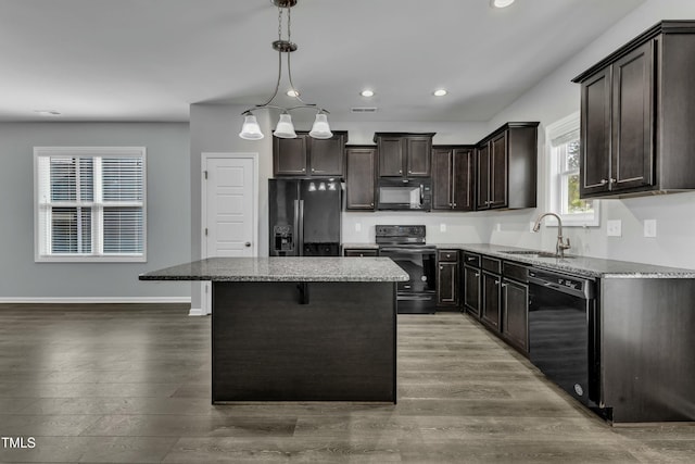 kitchen with stone counters, dark brown cabinetry, a sink, wood finished floors, and black appliances