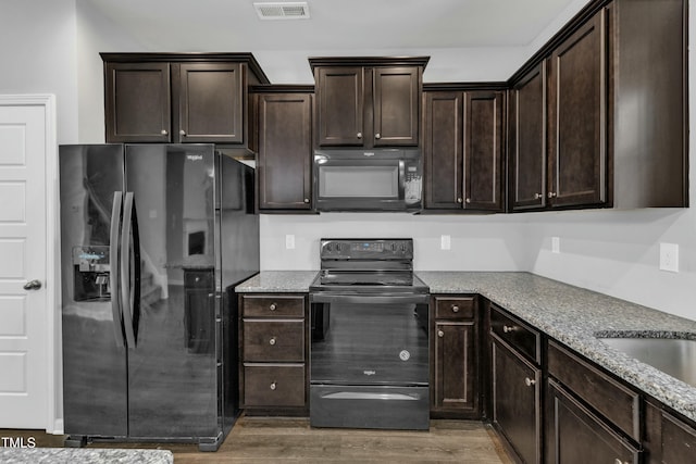 kitchen featuring black appliances, dark brown cabinets, wood finished floors, and visible vents