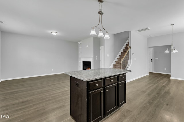 kitchen featuring dark wood-style floors, visible vents, open floor plan, a warm lit fireplace, and baseboards