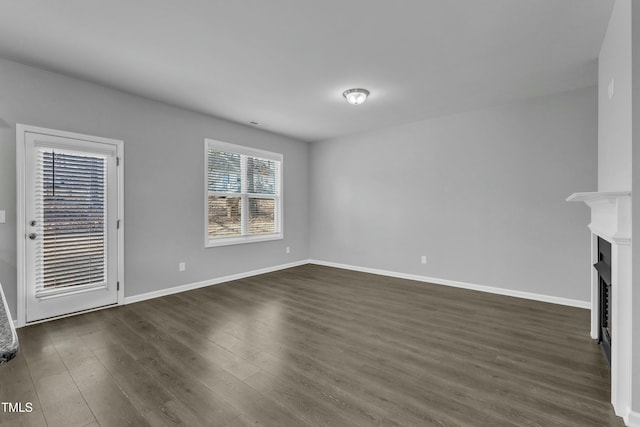 unfurnished living room featuring dark wood-style floors, a fireplace, and baseboards