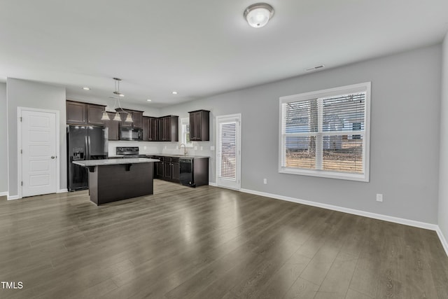 kitchen featuring dark brown cabinetry, visible vents, a center island, light countertops, and black appliances