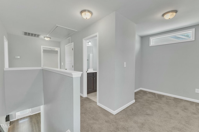 interior space featuring attic access, visible vents, light carpet, and baseboards