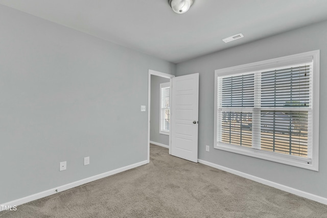 spare room with carpet, visible vents, and baseboards