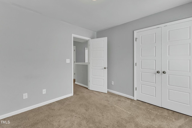 unfurnished bedroom featuring carpet floors, baseboards, and a closet