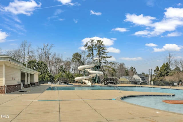 community pool featuring a water slide and a patio area