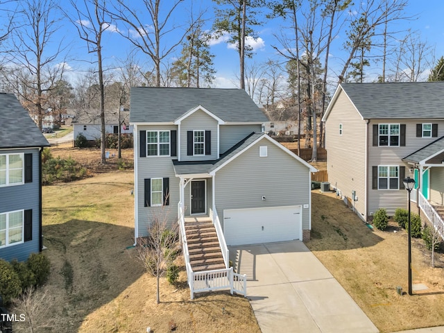 traditional home with stairs, concrete driveway, a front lawn, and roof with shingles