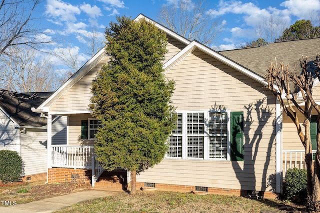 view of side of home featuring crawl space, a shingled roof, and a porch