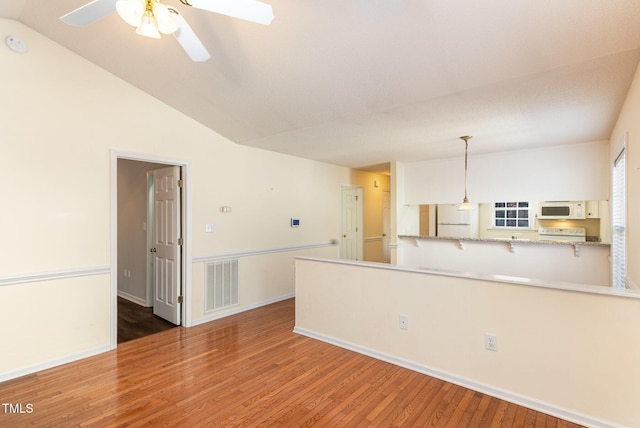 interior space featuring decorative light fixtures, visible vents, light countertops, white appliances, and a peninsula