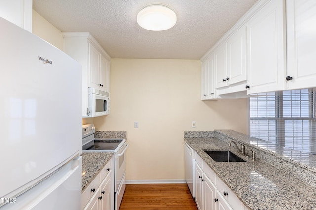 kitchen featuring dark wood-type flooring, white cabinetry, a sink, light stone countertops, and white appliances