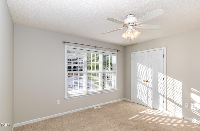 unfurnished room with light carpet, visible vents, baseboards, and a textured ceiling