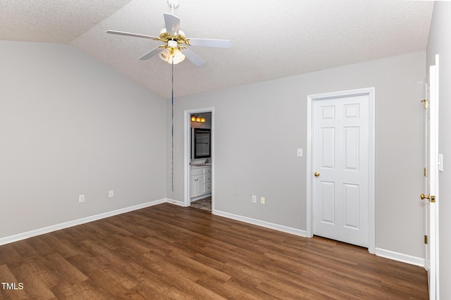 unfurnished bedroom featuring dark wood-style floors, baseboards, vaulted ceiling, and a textured ceiling