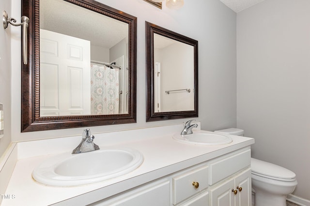 bathroom featuring a sink, a textured ceiling, toilet, and double vanity