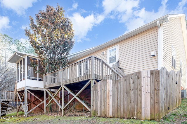 rear view of house with a sunroom, a wooden deck, and central AC unit