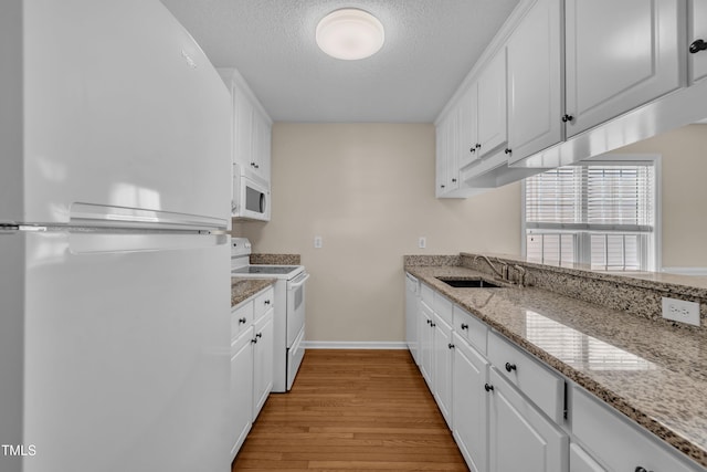 1614 W Cotton Gin Dr, Clayton, NC 27527 - kitchen featuring white appliances, a sink, light wood finished floors, a textured ceiling, and baseboards