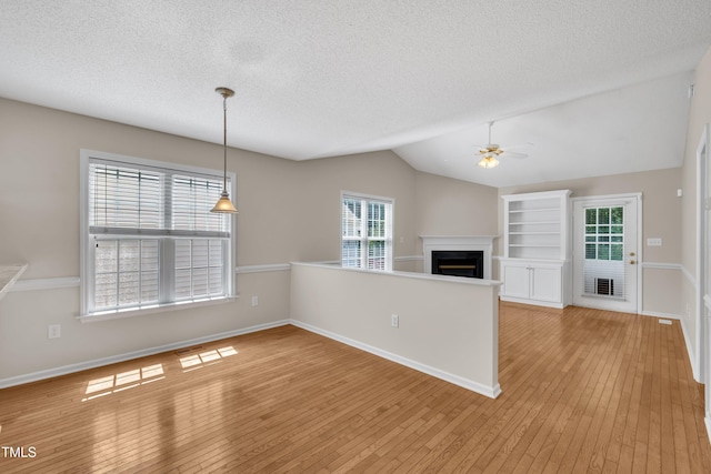 1614 W Cotton Gin Dr, Clayton, NC 27527 - unfurnished living room with ceiling fan, light wood finished floors, a fireplace, vaulted ceiling, and a textured ceiling