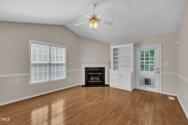 1614 W Cotton Gin Dr, Clayton, NC 27527 - unfurnished living room with a ceiling fan, lofted ceiling, light wood-style floors, a glass covered fireplace, and baseboards