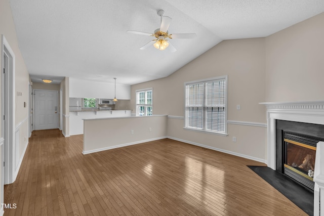 1614 W Cotton Gin Dr, Clayton, NC 27527 - unfurnished living room featuring wood-type flooring, a fireplace with flush hearth, a ceiling fan, lofted ceiling, and a textured ceiling