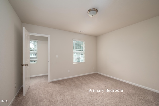 spare room with light carpet, visible vents, and baseboards