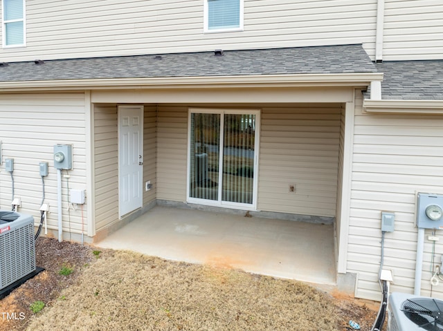 property entrance with a patio area, roof with shingles, and central air condition unit