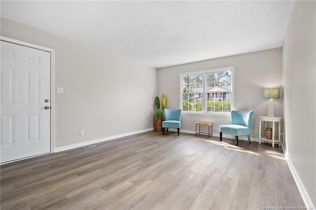 unfurnished room featuring a textured ceiling, baseboards, and wood finished floors