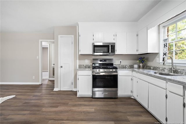 kitchen featuring appliances with stainless steel finishes, white cabinetry, a sink, and dark wood-type flooring