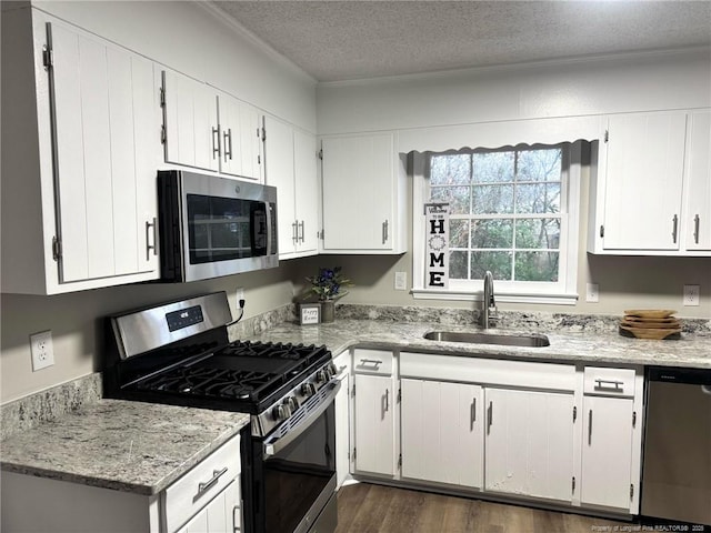 kitchen with a textured ceiling, appliances with stainless steel finishes, white cabinets, and a sink