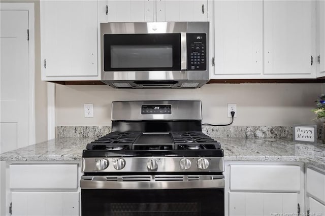 kitchen featuring appliances with stainless steel finishes, light stone countertops, and white cabinets