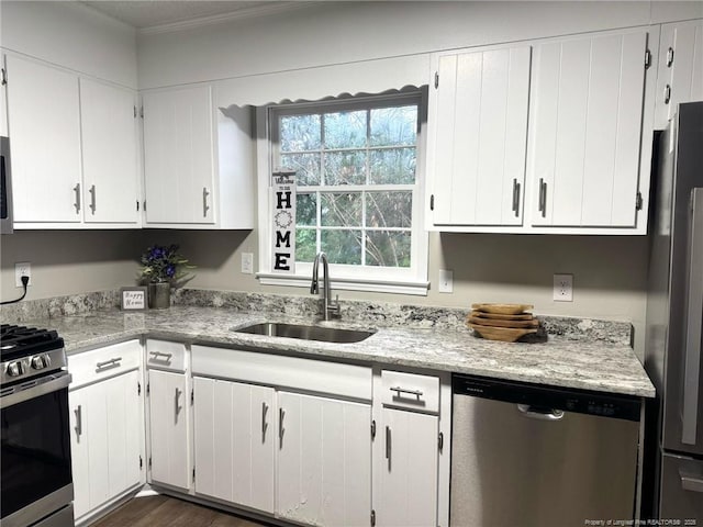 kitchen featuring ornamental molding, appliances with stainless steel finishes, a sink, and white cabinetry