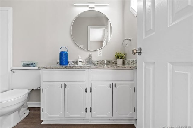 bathroom featuring wood finished floors, vanity, toilet, and baseboards