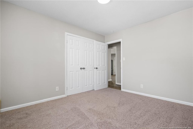 unfurnished bedroom with a closet, carpet, and baseboards