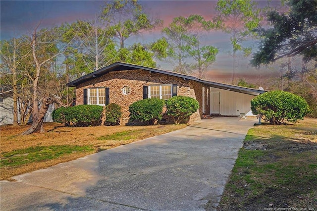 view of front of home featuring driveway, a carport, and brick siding