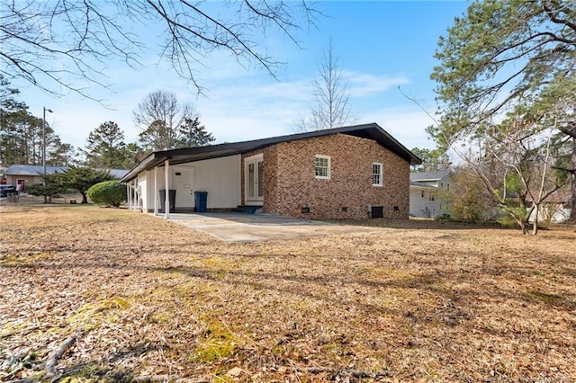 back of house with brick siding, crawl space, and a patio area