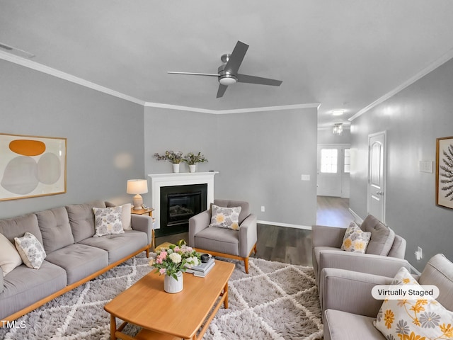 living room featuring ornamental molding, a glass covered fireplace, wood finished floors, and visible vents