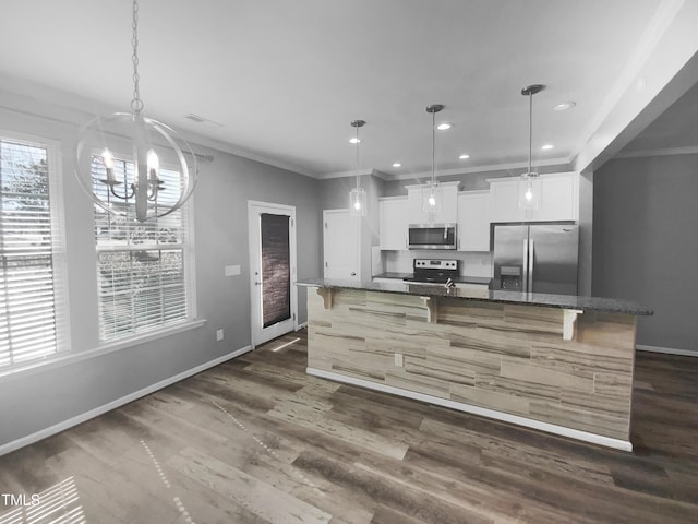 kitchen featuring dark stone counters, a spacious island, stainless steel appliances, white cabinetry, and pendant lighting