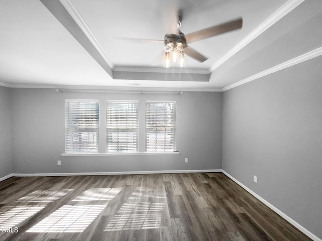 spare room with baseboards, a raised ceiling, a ceiling fan, dark wood-style flooring, and crown molding